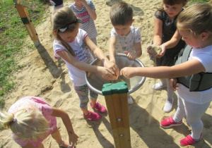 dzieci sypią piach do lejka umieszczonego w piaskownicy na drewnianym palu i obserwują jego działanie